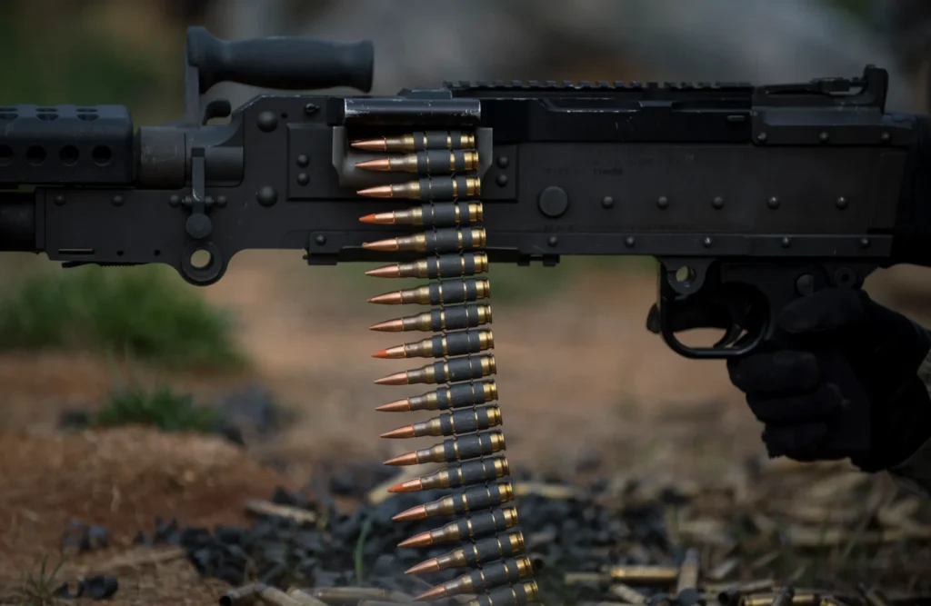 Close-up of a machine gun with ammunition belt, demonstrating the precision of laser marking for firearm components.