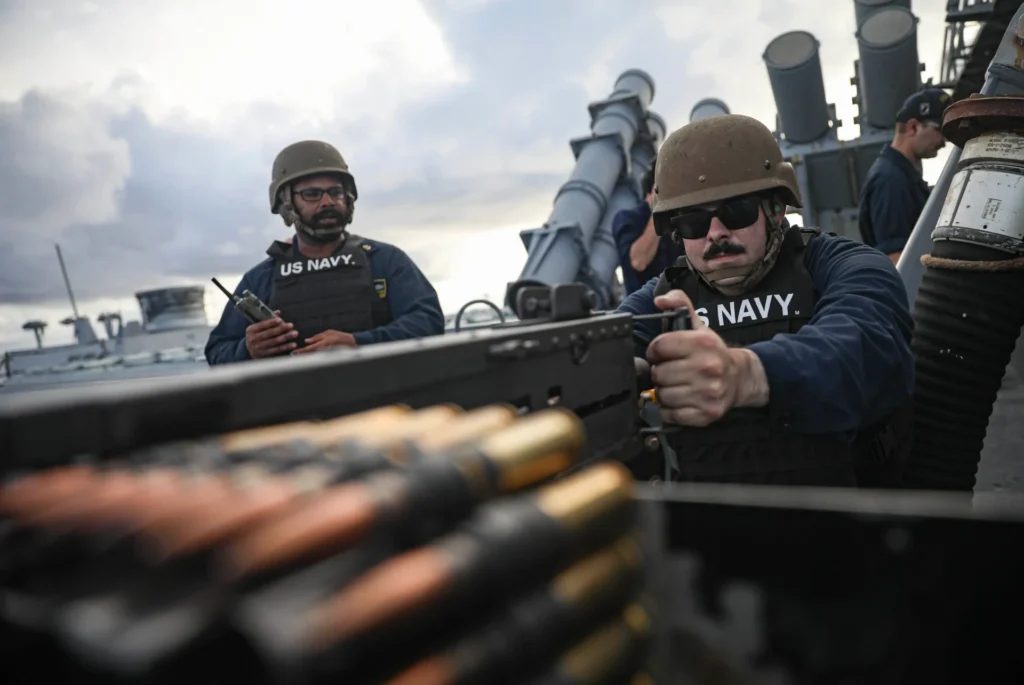 US Navy personnel operating a machine gun with ammunition belt, showcasing potential applications for laser marking on military equipment.